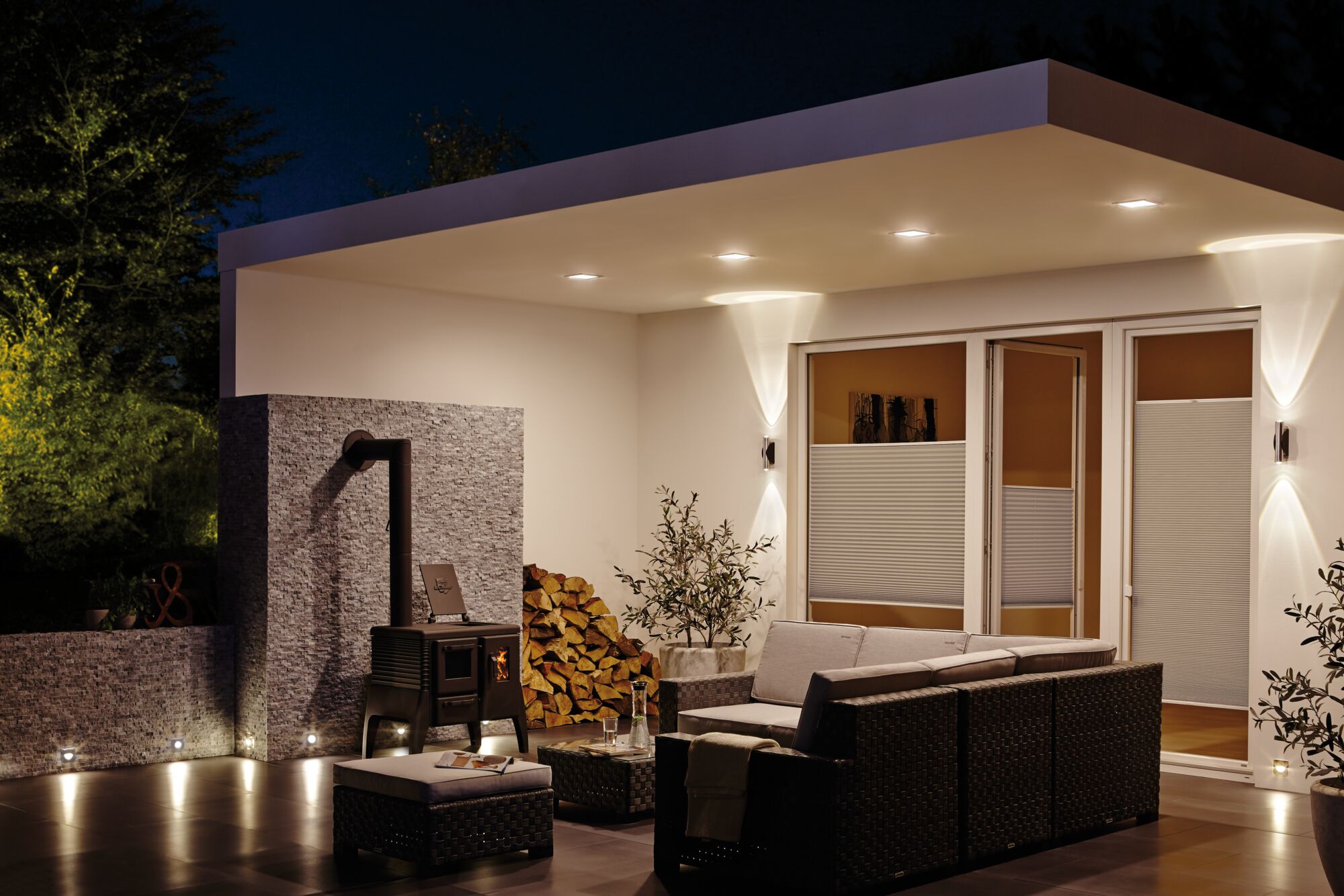 Moderne terrasverlichting met warmwitte LED-wand- en vloerinbouwlampen in gezellige buitenruimte.