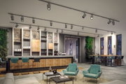 Moderne graue LED-Schienenstrahler an Decke in stilvollem Restaurant mit Holz- und Grünakzenten