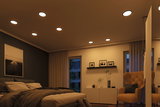 Modern bedroom with warm white LED recessed ceiling lights and a cozy brown armchair.