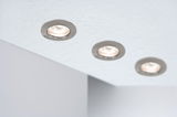 Trois spots encastrés ronds en acier inoxydable brossé dans un plafond blanc pour éclairage intérieur moderne