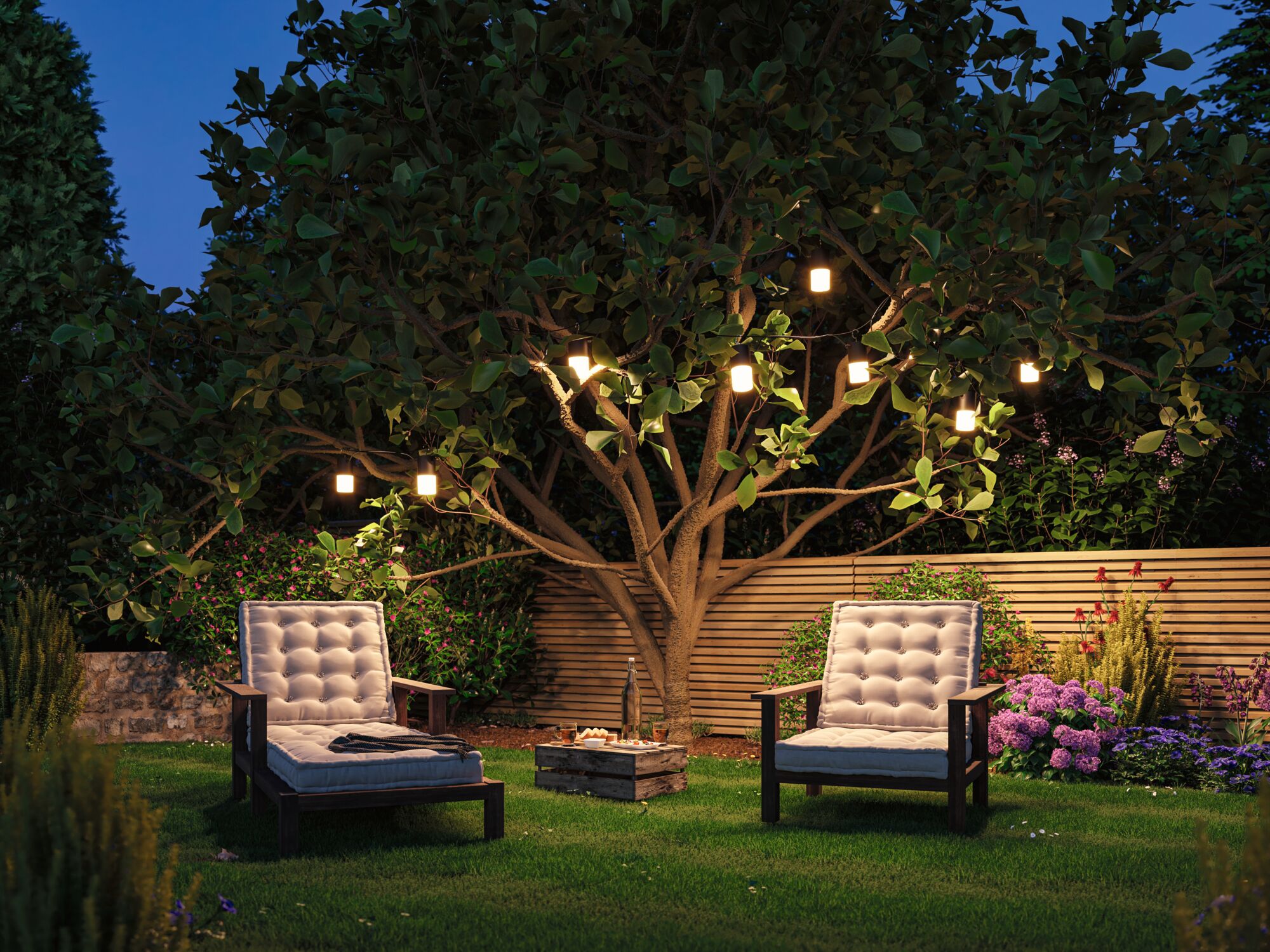 Gemütliche Gartenstühle mit hellen Polstern unter Baum mit warmweißen LED-Lichterketten im Garten.