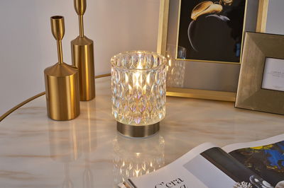 Lampe de table décorative en verre texturé clair avec lumière blanche chaude sur surface en marbre.