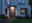 Éclairage extérieur moderne avec anneau LED blanc chaud au-dessus de la porte grise et chemin de jardin