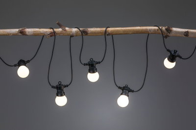 Lyskæde med fem varm-hvide LED-pærer på sort kabel, dekorativt hængt på en gren