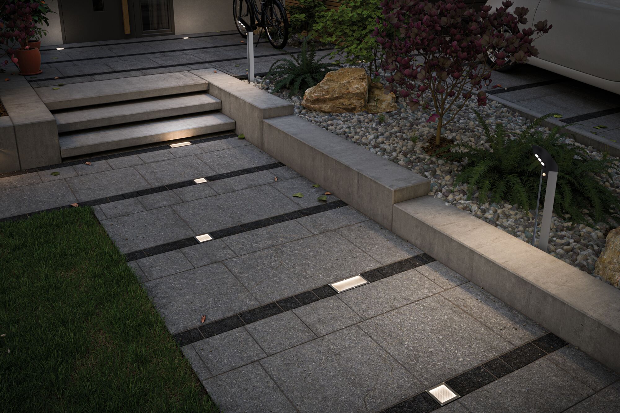 Moderne Außenbeleuchtung mit eingelassenen LED-Bodenleuchten und Pollerleuchte in grauem Steinweg.