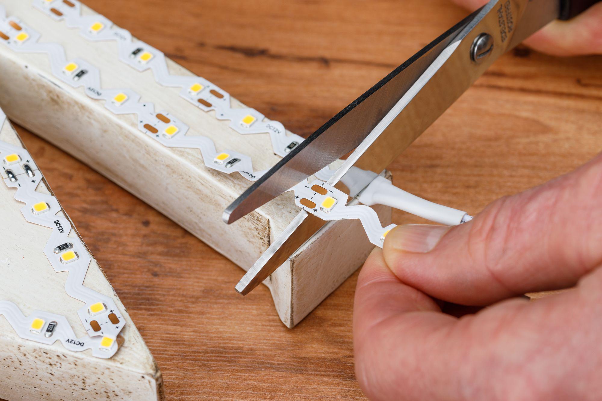 Hand knipt witte LED-strip met gele lampjes op houten ondergrond voor flexibele verlichting