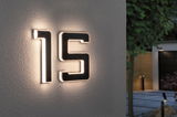 House number 15 with black solar LED lighting on white exterior wall for outdoor use