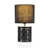 Elegant table lamp with black fabric shade and patterned smoked glass base for ambient lighting