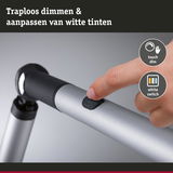 Vinger drukt op touch dimschakelaar op zilveren aluminium lampenarm voor traploze lichtregeling