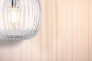 Nahaufnahme einer klaren gerillten Glaslampe mit warmweißem LED-Leuchtmittel für Wohnraumbeleuchtung