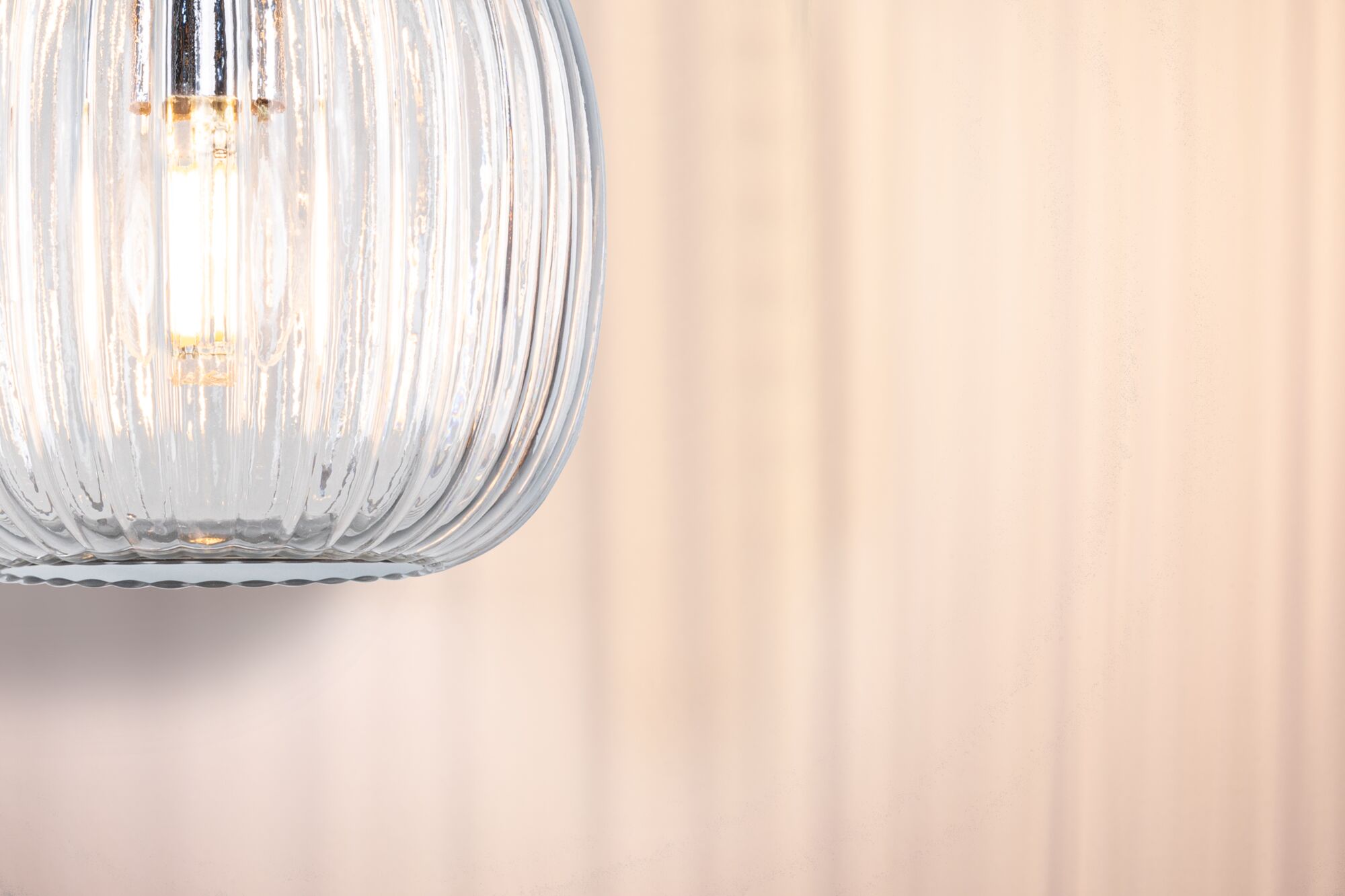 Nahaufnahme einer klaren gerillten Glaslampe mit warmweißem LED-Leuchtmittel für Wohnraumbeleuchtung