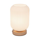 Table lamp with ribbed white glass and gold metal base for ambient lighting in living spaces