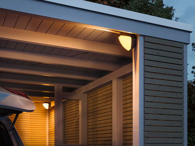 Außenwandleuchte mit warmweißem Licht an moderner Holzgarage in Grau und Naturholz für Außenbeleuchtung.