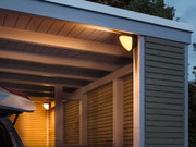 Außenwandleuchte mit warmweißem Licht an moderner Holzgarage in Grau und Naturholz für Außenbeleuchtung.