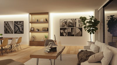 Salon moderne avec éclairage LED indirect, table en bois, canapé et tableaux décoratifs en noir et blanc.
