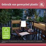 Verlichte tafellamp van gerecycled plastic op balkon met planten en boek in de avond