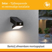 Zwarte solar buitenwandlamp met bewegingssensor op grijze muur, energiezuinige LED-verlichting