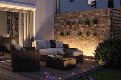 Salon de jardin confortable en polyrattan avec éclairage LED au sol sur terrasse en bois au crépuscule