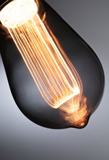 Close-up of warm glowing vintage glass light bulb with visible filament for decorative lighting use