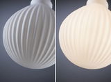 White ribbed glass lampshade close-up, left off, right illuminated, modern lighting design