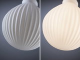 White ribbed glass lampshade close-up, left off, right illuminated, modern lighting design