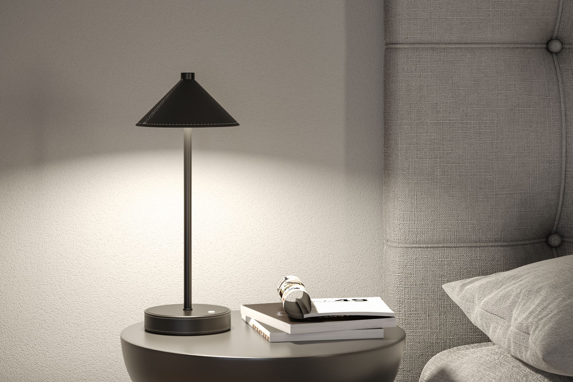 Lampe de table noire en métal avec abat-jour conique sur table de chevet grise près d’une tête de lit rembourrée.