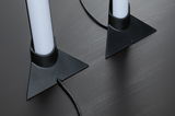 Two white LED lights with black triangular plastic bases on dark wood table, visible cables