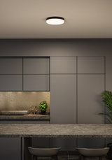 Round ceiling light with black frame and white diffuser in modern kitchen with grey cabinets.