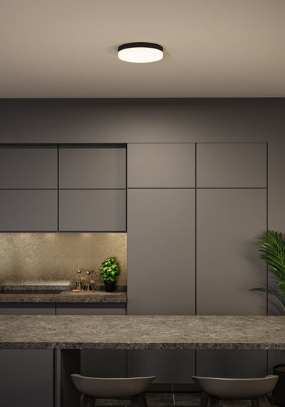 Round ceiling light with black frame and white diffuser in modern kitchen with grey cabinets.