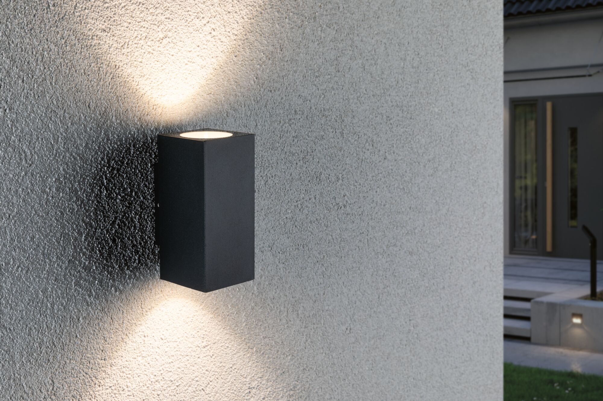 Schwarze Aluminium-Wandleuchte mit Up- und Downlight an grauer Außenwand für moderne Außenbeleuchtung