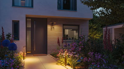 Moderne buitenverlichting met warmwitte LED-padverlichting en huisnummer op houten gevel bij ingang.