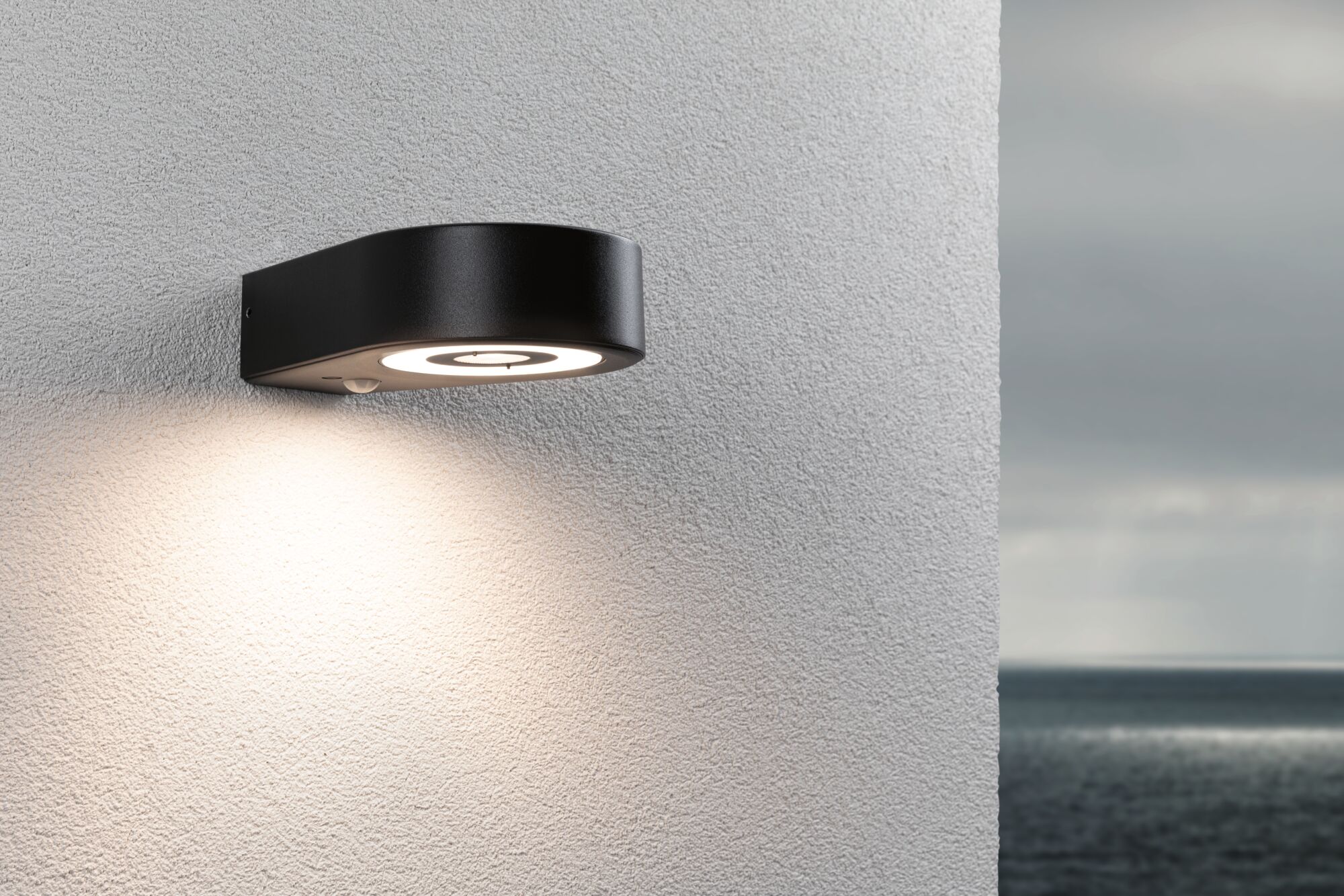 Schwarze LED-Außenwandleuchte aus Metall mit rundem Design und warmweißem Licht für Hausfassaden.