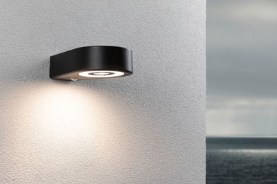 Black metal LED outdoor wall light with round design and warm white illumination for home exteriors.