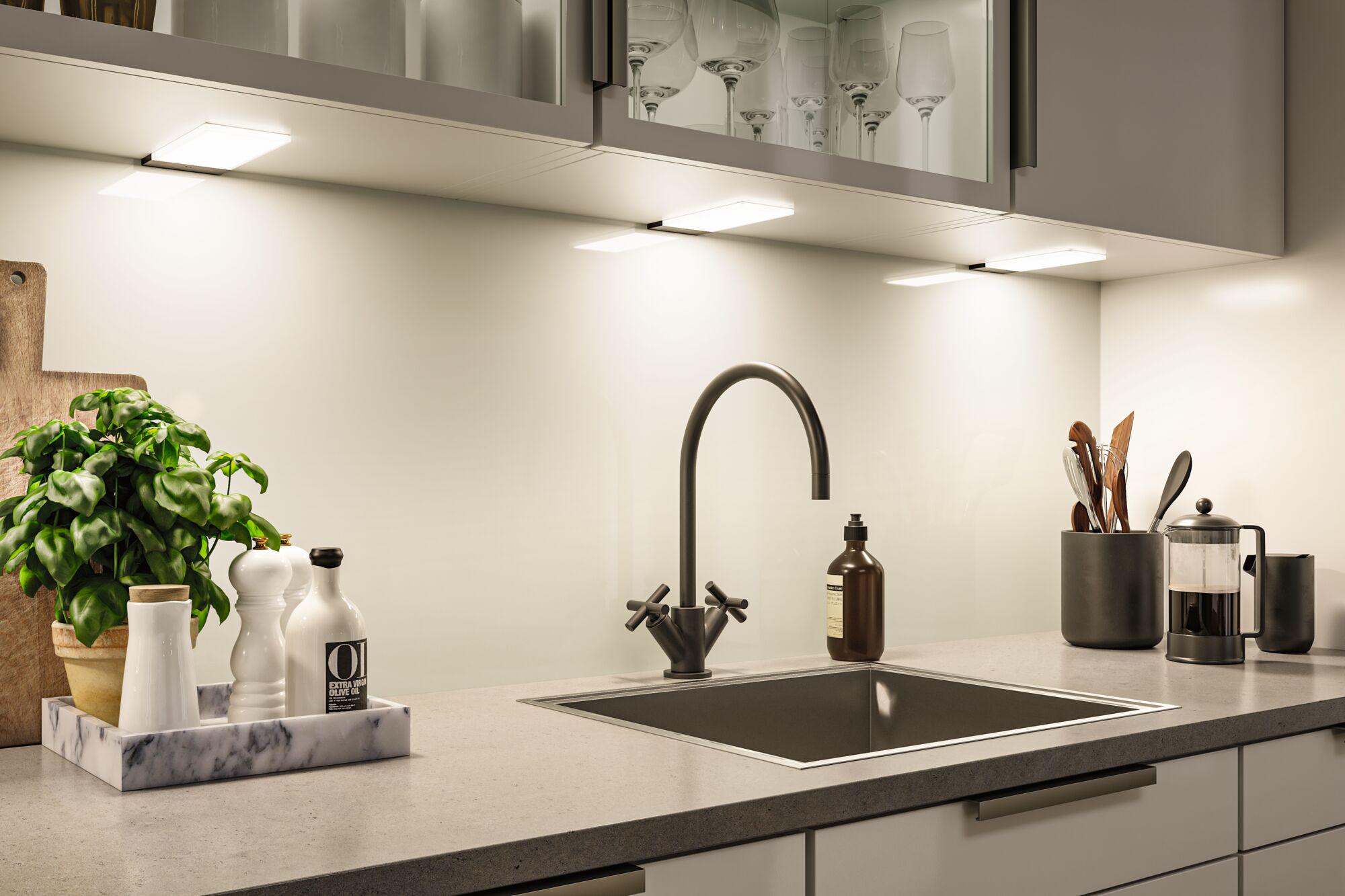 Modern kitchen countertop with stainless steel sink, black faucet, and LED under-cabinet lights for bright illumination
