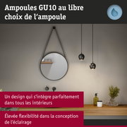 Salle de bain moderne avec miroir rond, suspensions noires, étagère en bois avec plantes et produits de soin