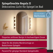 Spiegelleuchte Regula II in Chrom mit warmweißem Licht neben ovalem Badezimmerspiegel
