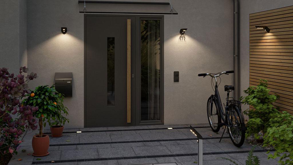 Moderne husindgang med grå dør, væg- og gulvlamper i aluminium til udendørsbelysning.