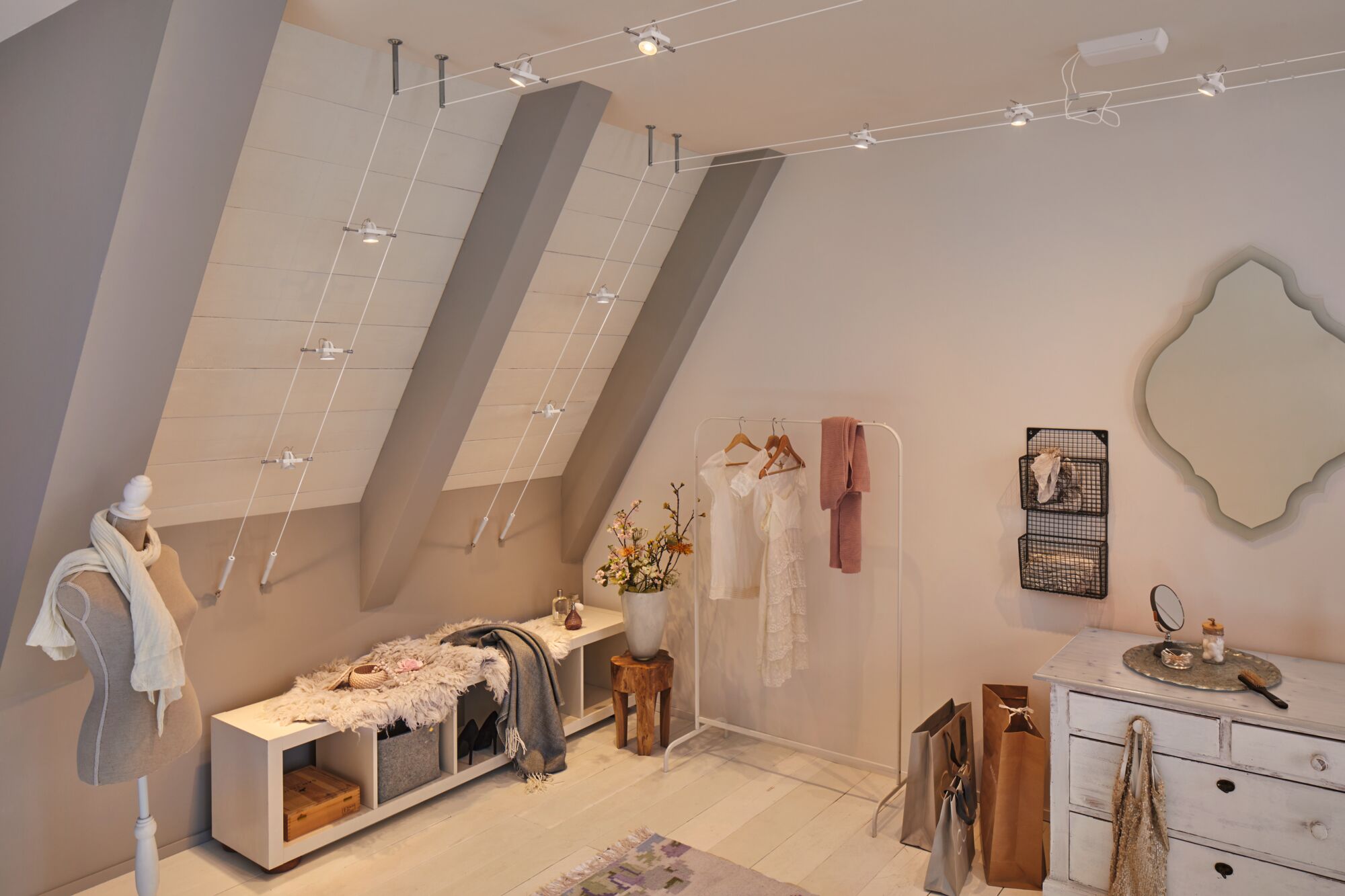 Modern dressing room with white wooden cabinet, clothes rack, and minimalist cable lighting system.