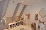 Modern dressing room with white wooden cabinet, clothes rack, and minimalist cable lighting system.