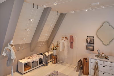 Modern dressing room with white wooden cabinet, clothes rack, and minimalist cable lighting system.