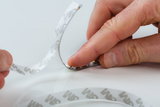 Hand peeling protective film from flexible LED strip light with adhesive backing for easy installation