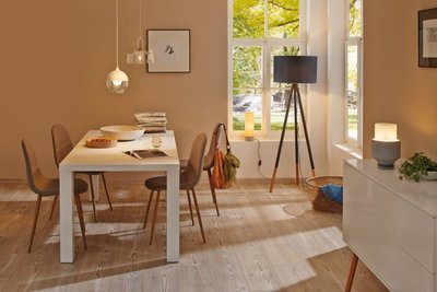 Salle à manger moderne avec table blanche, chaises marron et différentes lampes pour un éclairage chaleureux