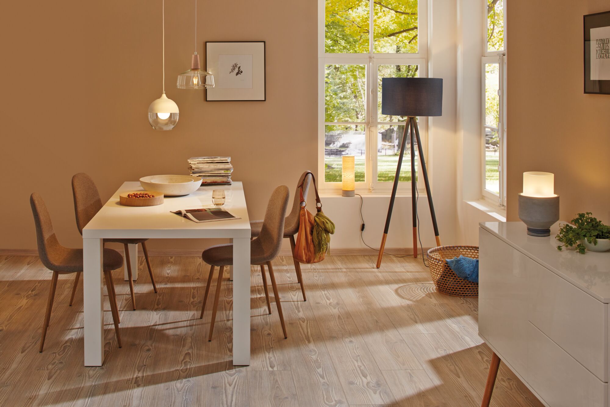 Salle à manger moderne avec table blanche, chaises marron et différentes lampes pour un éclairage chaleureux