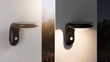 Black plastic solar wall light with motion sensor, day and night view, outdoor lighting
