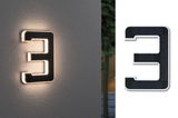 Illuminated house number 3 in black solar material with warm white LED light on grey wall.