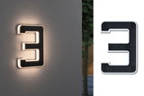 Illuminated house number 3 in black solar material with warm white LED light on grey wall.