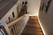 Escalier en bois moderne avec rambarde blanche et éclairage LED indirect sur le mur dans un espace de vie.