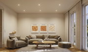 Modernes Wohnzimmer mit grauem Stoffsofa, Sessel, Hocker und Holztisch auf hellem Teppich.