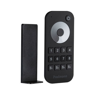 Black plastic remote control with buttons and holder for indoor lighting control