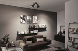 Moderner Wohnraum mit schwarzer Deckenleuchte aus Metall, grauer Wand und braunem Sofa mit Kissen